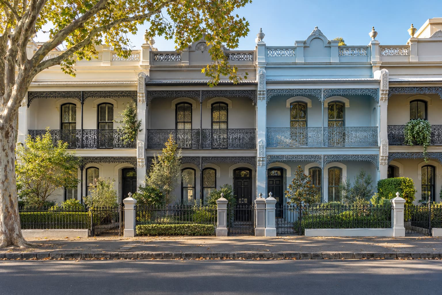 A row of restored two-storey Victorian terraces with cast-iron lace balconies on a quiet inner-Melbourne street.